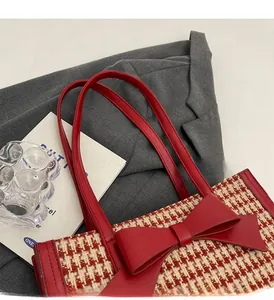 Dettaglio della borsa tote in tweed rosso con un grande fiocco e manici robusti