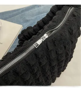 Detail of a smooth silver metal zipper on a black textured nylon dumpling bag fabric