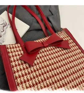 Dettaglio della borsa tote rossa pied de poule con grande fiocco in pelle e manici robusti