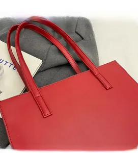 Dettaglio ravvicinato di cuciture e tracolla della borsa tote in ecopelle rossa