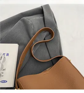 Close-up of brown pebbled leather texture and reinforced handle stitching on tote bag