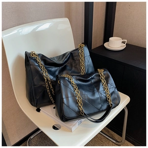 Detail of black quilted leather tote bags with chunky gold chain straps in two sizes