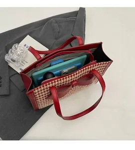 Interno spazioso di una borsa tote con motivo pied-de-poule, fiocco e oggetti personali