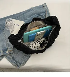 Detailed interior of a black nylon dumpling bag showing large capacity for gadgets