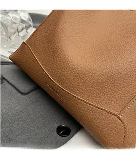Macro shot of caramel brown lychee leather texture and logo embossing on tote bag