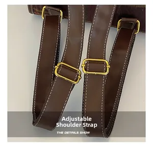Detail of adjustable brown leather shoulder straps with golden buckles and white stitching