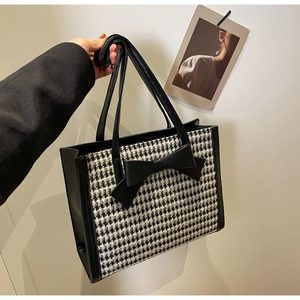 Dettaglio della borsa tote pied-de-poule con fiocco in pelle nera e trama premium