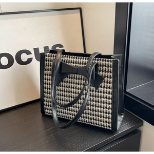Dettaglio della borsa tote pied de poule con un elegante fiocco decorativo in pelle nera