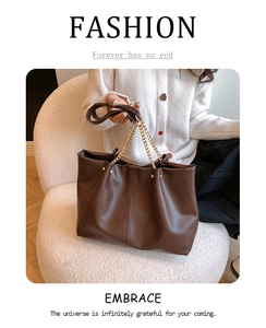 Detail view of large dark brown leather tote bag with gold chain and vertical stitching