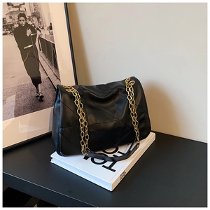 Close-up of quilted black leather texture and gold chain straps on the tote bag