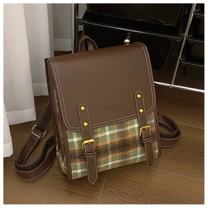 Close-up of retro backpack featuring brown leather, green plaid fabric, and gold buckles