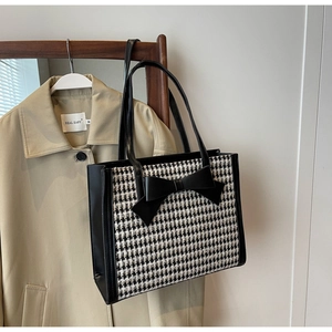 Vista dettagliata della borsa tote pied de poule con grande fiocco in pelle su gruccia