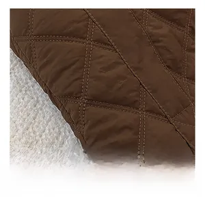 Detailed macro view of dark brown quilted nylon fabric with diamond patterns and glossy texture