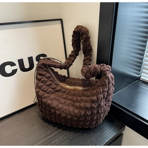 Close-up of dark brown bubble textured nylon fabric and silver zipper on the crescent bag