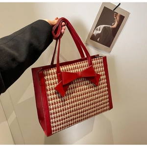 Dettaglio della borsa tote in tweed a quadri rossi con fiocco e tracolla in pelle