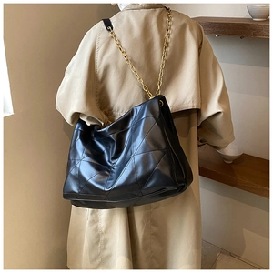 Detail of black quilted leather shoulder bag with glossy gold chunky chain straps