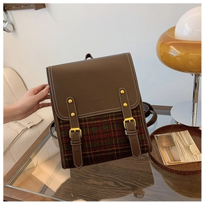 Detail of vintage brown leather and plaid fabric backpack with gold buckle straps