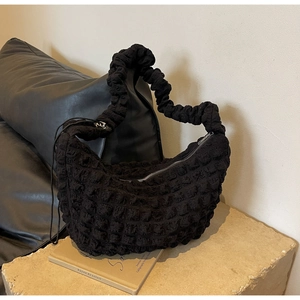 Macro detail of black bubble texture nylon bag with ruffled handle on stone base