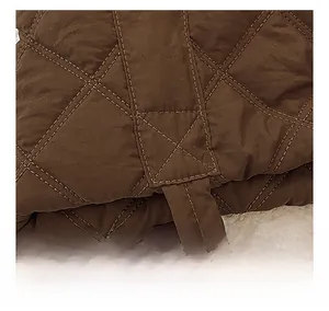Close-up of diamond quilted nylon fabric with reinforced stitching and dark brown texture