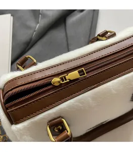 Détail d'un sac à main en peluche blanche avec garniture en cuir brun et zip doré