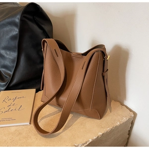 Detailed view of brown litchi pattern leather bucket bag with wide shoulder strap