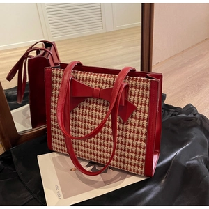 Dettaglio della borsa tote a pied-de-poule rossa con un grande fiocco e finiture in pelle