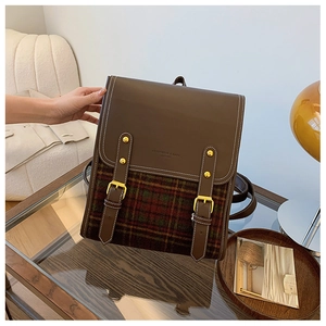 Detail of vintage brown leather and red-green plaid pattern backpack with gold buckles