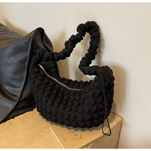 Close-up of black bubble textured nylon shoulder bag with ruffled strap and zipper