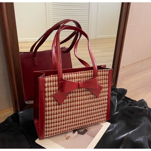 Dettaglio della borsa tote houndstooth rossa con fiocco grande e manici in pelle