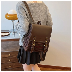 Detail of vintage retro backpack with plaid stitching and gold buckle straps on back