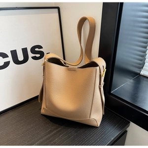 Detailed close-up of beige lychee grain leather bucket bag with gold metal buckle