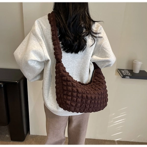 Detail of a dark brown bubble textured crossbody bag shown on a model with neutral clothing