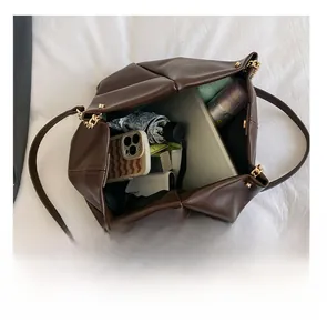 Top view of large brown tote bag interior filled with daily essentials and tablet