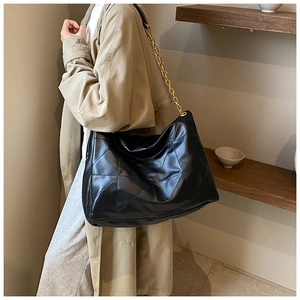 Close-up of quilted tote bag with golden chain strap on a trench coat model