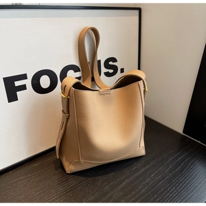 Close-up of light brown lychee grain leather bucket bag with gold metal buckle detail