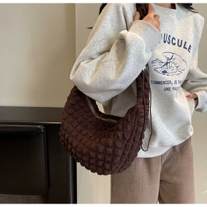 Detail shot of the deep brown quilted nylon fabric and crescent dumpling bag texture