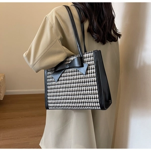 Dettaglio di una borsa tote pied-de-poule con fiocco nero e rifiniture in ecopelle