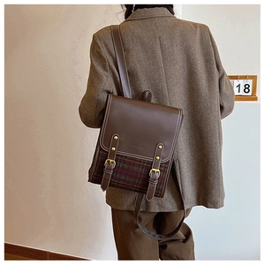 Detailed view of British style retro backpack with brown leather and plaid fabric stitching