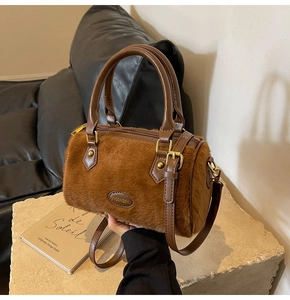 Détail du sac Boston en fausse fourrure marron avec poignées en cuir et logo en métal