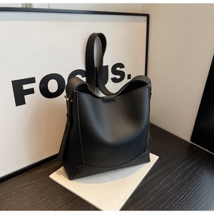 Close-up of black pebbled leather bucket bag with gold hardware and wide shoulder strap