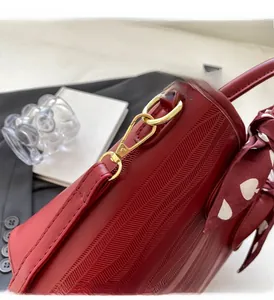 Close-up of red embossed leather bag featuring gold hardware and silk scarf detail