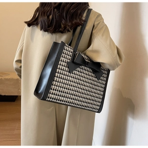 Dettaglio della borsa tote pied-de-poule con grande fiocco nero su una modella