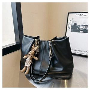 Detail of large black tote bag with chain strap and a cute bunny plush charm