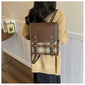 Detailed side view of vintage British style plaid backpack with leather strap and gold buckle