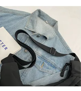 Close-up of black nylon crossbody bag featuring adjustable strap and woven zipper pull