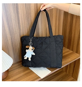 Detail of black quilted nylon tote bag with rhombus pattern and cute dog plush charm