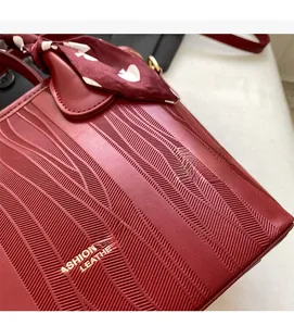 Close-up of red textured leather handbag with gold lettering and decorative polka dot scarf