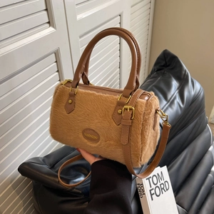 Gros plan du sac oreiller en peluche marron montrant la fausse fourrure et le logo