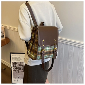 Lifestyle shot showing a retro plaid backpack with brown leather accents and gold buckles
