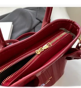 Detail view of smooth golden metal zipper and spacious interior on a red leather bag